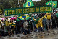 FILE - Supporters of President Jair Bolsonaro hold a sign with a message that reads in Portuguese: "The people ask the army for help" during a protest against his defeat in the presidential runoff election, in Rio de Janeiro, Brazil, Nov. 2, 2022. Supporters of incumbent President Jair Bolsonaro who refuse to accept his narrow defeat in October’s election have blocked roads and camped outside military buildings while pleading for intervention from the armed forces or marching orders from their commander in chief. (AP Photo/Bruna Prado, File)