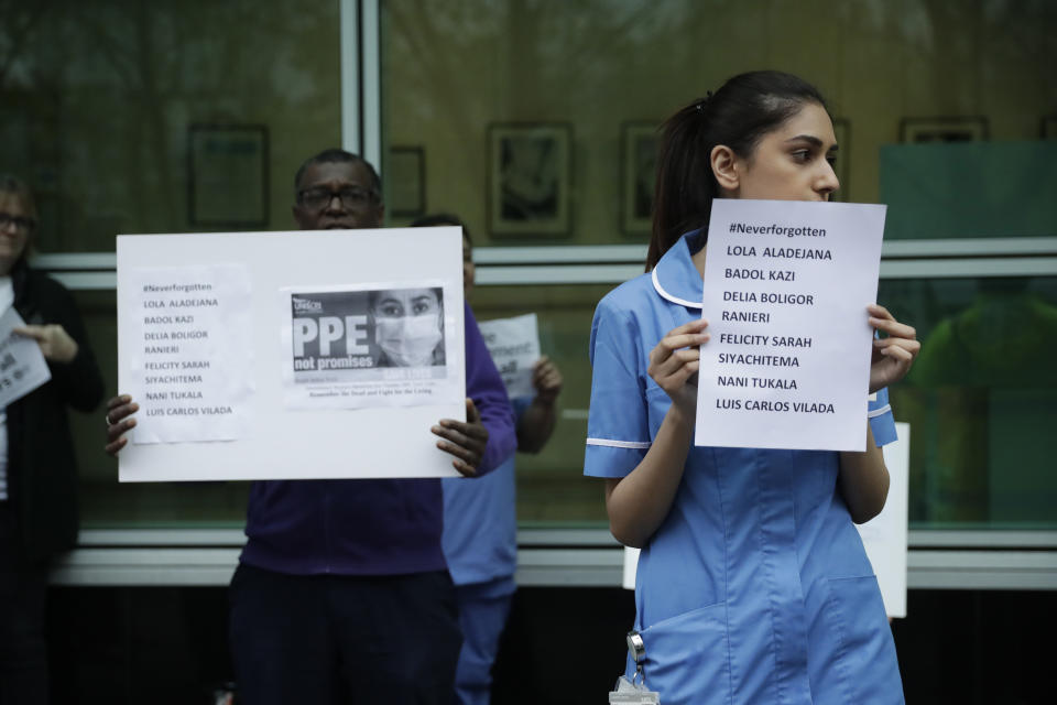 Hospital workers hold placards with the names of their colleagues who have died from coronavirus as they take part in a protest calling on the British government to provide PPE (personal protective equipment) across Britain for all workers in care, the NHS (National Health Service) and other vital public services after a nationwide minute's silence to remember medical staff and key workers that have died from the coronavirus, at University College Hospital in London, Tuesday, April 28, 2020. One of the protesters stressed the point that their hospital Trust has good levels of PPE and that they want the government to provide more PPE to people elsewhere that don't have enough. (AP Photo/Matt Dunham)