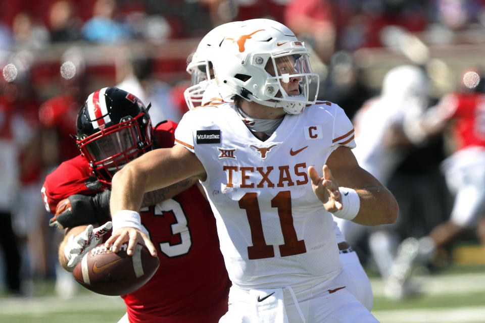 Texas quarterback Sam Ehlinger passes downfield under pressure from defensive lineman Eli Howard during the first half of an NCAA college football game against Texas Tech, Saturday Sept. 26, 2020, in Lubbock, Texas. (AP Photo/Mark Rogers)
