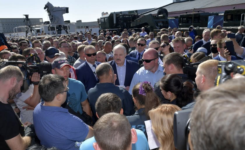 Belarusian President Alexander Lukashenko, center, surrounded by his bodyguards listens to an employee of the Minsk Wheel Tractor Plant in Minsk, Belarus, Monday, Aug. 17, 2020. Workers heckled President Alexander Lukashenko as he visited a factory and strikes grew across Belarus, raising the pressure on the authoritarian leader to step down after 26 years in office. (Andrei Stasevich/BelTA Pool Photo via AP)