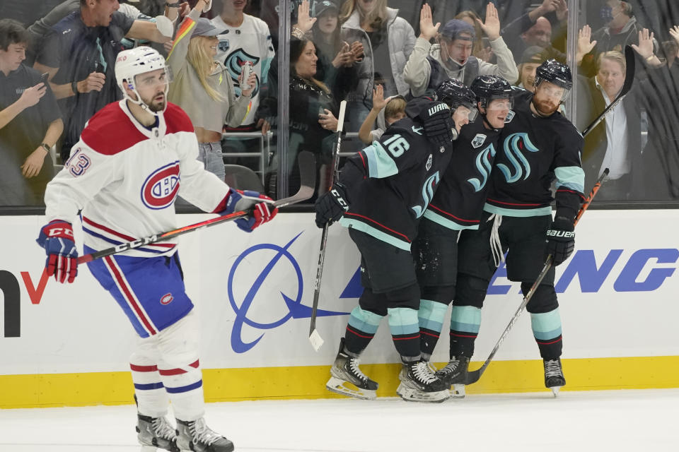 Seattle Kraken center Ryan Donato, second from right, celebrates with teammates Jared McCann (16) and Adam Larsson, right, as Montreal Canadiens center Cedric Paquette (13) looks on after Donato scored a goal during the third period of an NHL hockey game, Tuesday, Oct. 26, 2021, in Seattle. The Kraken won 5-1. (AP Photo/Ted S. Warren)