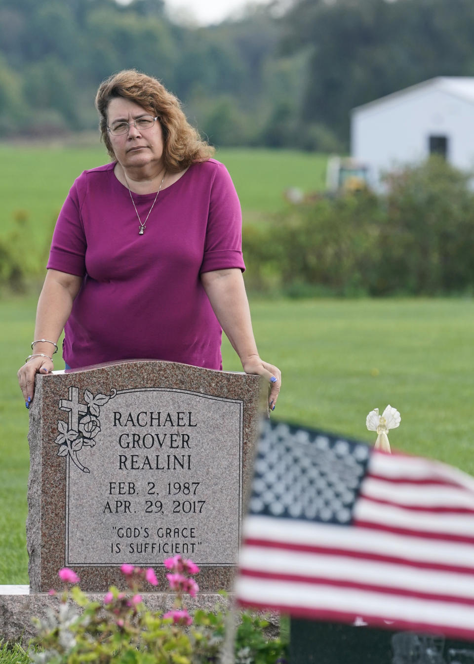 Sharon Grover stands over the grave of her daughter, Rachael, Tuesday, Sept. 28, 2021, at Fairview Cemetery in Mesopotamia, Ohio. Grover believes her daughter started using prescription painkillers around 2013 but missed any signs of her addiction as her daughter, the oldest of five children, remained distanced. A “bellwether trial is set to start Monday in federal court in Cleveland to determine whether retail pharmacy chains are liable for opioid crisis costs in two Ohio counties. Grover lives in Trumbull County, Ohio, which along with Lake County, have sued four retail pharmacy chains to recover “public nuiscance” costs the opioid crisis continues to inflict on their communities. (AP Photo/Tony Dejak)