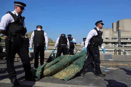 A police officer removes a carpet during the Extinction Rebellion protest on Waterloo Bridge in London, Britain April 20, 2019. REUTERS/Simon Dawson