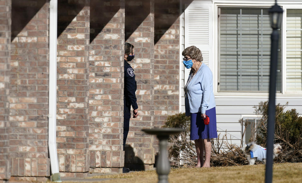 A police officer, left, talks to a resident as she walks her dog outside the front door of the Legacy Assisted Living at Lafayette care facility, Wednesday, Feb. 3, 2021, in Lafayette, Colo. A 95-year-old resident of the assisted care home was taken into police custody Wednesday after allegedly shooting an employee at the center. (AP Photo/David Zalubowski)