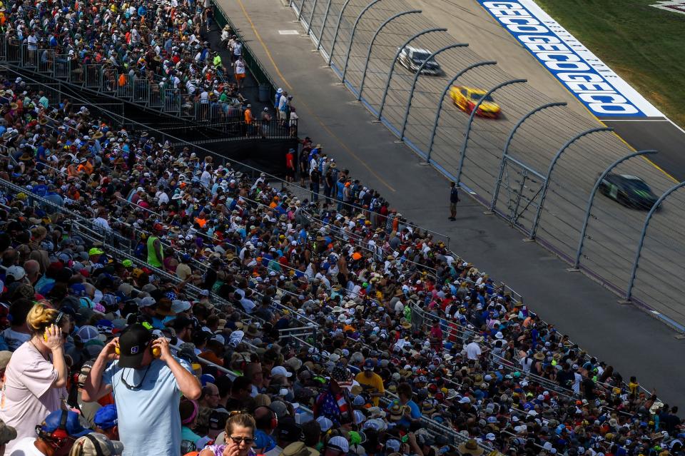 Race fans adjust ear protection in the grandstand as cars zip past during the NASCAR Cup Series Ally 400 race at the Nashville Superspeedway in Lebanon, Tenn., Sunday, June 20, 2021.