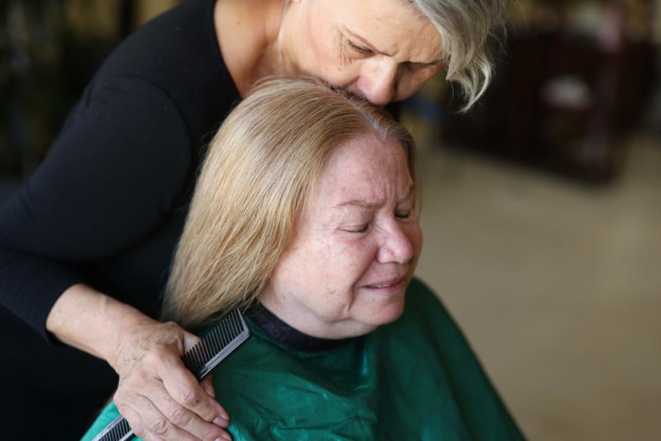 A hairdresser kisses her client's head