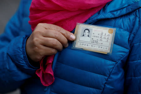 Former employee Huang Huiqun poses with her badge in front of the Sanyo electronics factory where she used to worked since 1985, in the Shekou area of Shenzhen, Guangdong Province, China, December 14, 2018. "When we arrived, there was only one road in Shenzhen, Shennan boulevard. It was the only road to Shekou. Sanyo was the only factory there. And all the buildings were low, only 4-5 floors tall. There were no skyscrapers," Huang recalled early years at Sanyo. Picture taken December 14, 2018. REUTERS/Thomas Peter