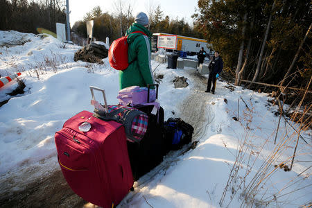 A man talks to a Royal Canadian Mounted Police (RCMP) officer before crossing the US-Canada border into Canada in Champlain, New York, U.S., February 14, 2018. REUTERS/Chris Wattie