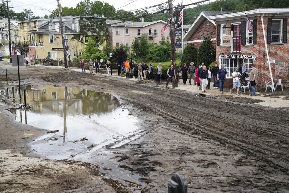 Governor Kathy Hochul and an entourage of emergency workers and journalists pass along Main Street, Monday, July 10, 2023, in Highland Falls, N.Y. Heavy rain has washed out roads and forced evacuations in the Northeast as more downpours were forecast throughout the day. One person in New York's Hudson Valley has drowned as she was trying to leave her home. (AP Photo/John Minchillo)