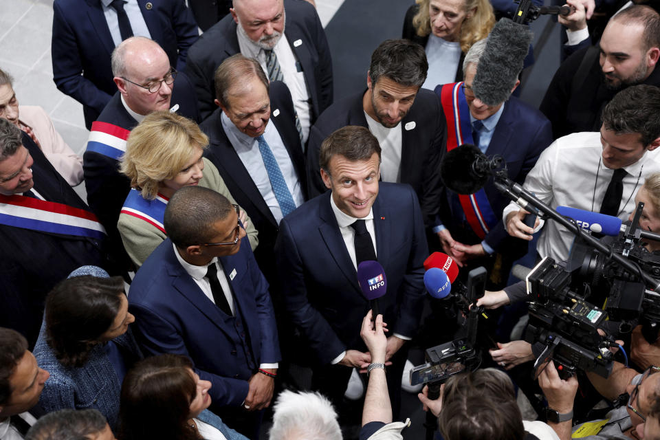 French President Emmanuel Macron, center, speaks to journalists during the inauguration of the Olympic Aquatics Center (CAO) in Saint-Denis, near Paris, Thursday, April 4, 2024. The aquatic center will host the artistic swimming, water polo and diving events during the Paris 2024 Olympic Games. (Gonzalo Fuentes/Pool via AP)