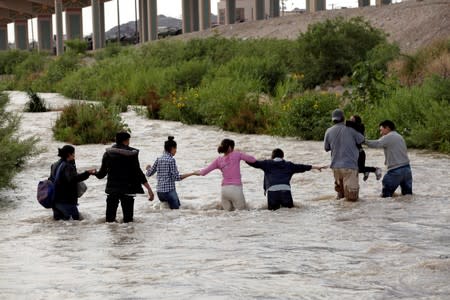 Migrants from Central America form a human chain to cross the Rio Bravo river as seen from Ciudad Juarez