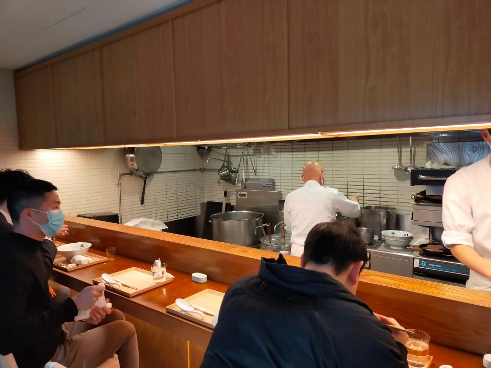 Chukasoba Ginza Hachigou ramen bar, view of open kitchen with chef pouring ramen in the background