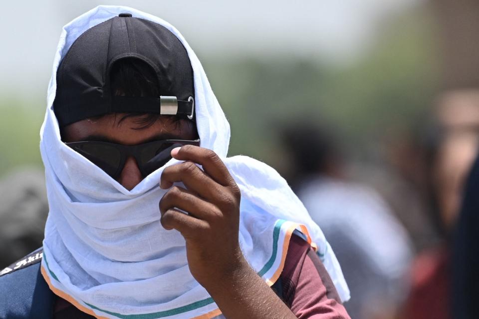 A man uses a scarf to shelter from the heat during a hot day in New Delhi on April 19, 2023.