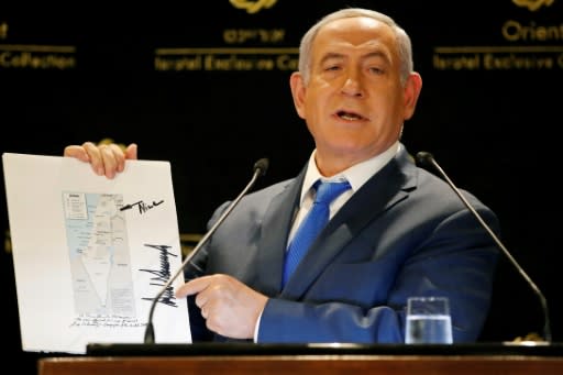 Israeli Prime Minister Benjamin Netanyahu displays a map of Israel, signed by US President Donald Trump, showing the Golan Heights as being inside Israel's borders