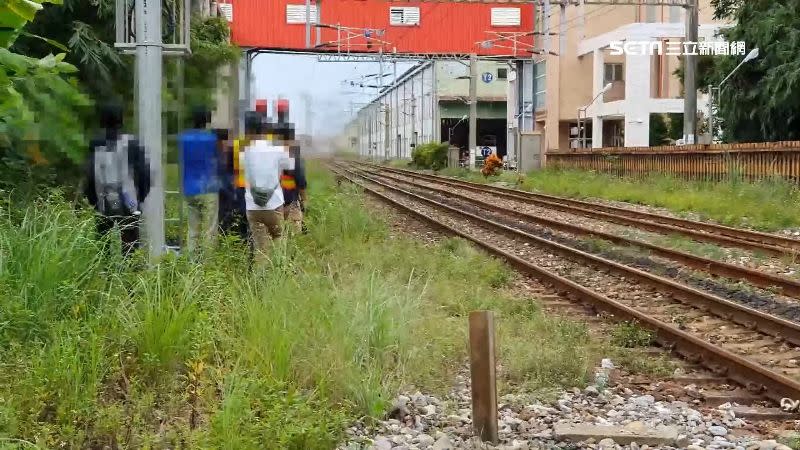 鐵道迷身穿台鐵工作人員的背心，站在鐵軌旁拍照。