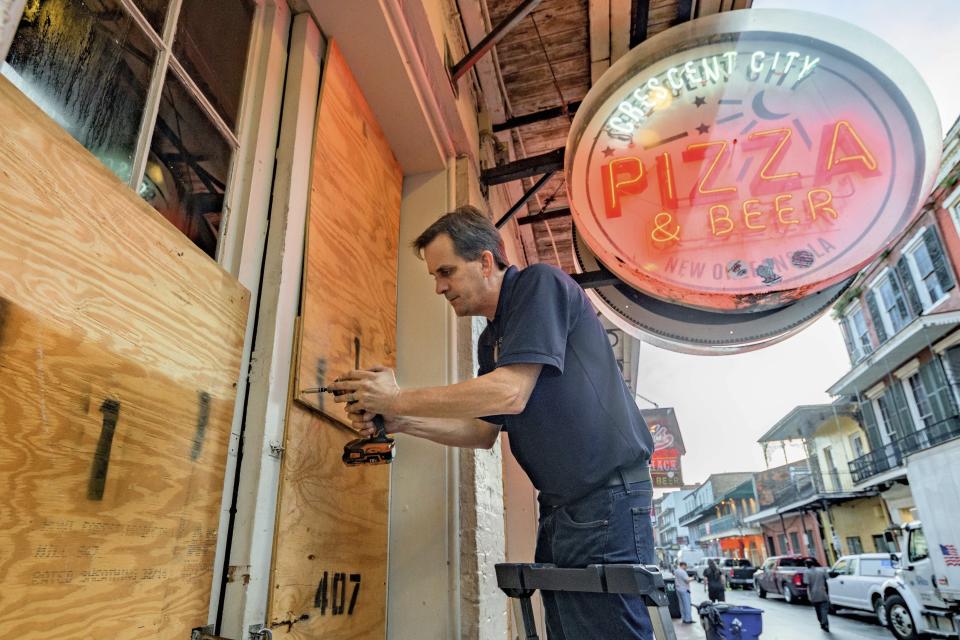 Michael Richard of Creole Cuisine Restaurant Concepts boards up Crescent City Pizza on Bourbon Street in the French Quarter before landfall of Hurricane Ida in New Orleans, Saturday, Aug. 28, 2021. Richard said the group is planning to board up and protect 34 restaurants owned by the company for the storm. (AP Photo/Matthew Hinton)