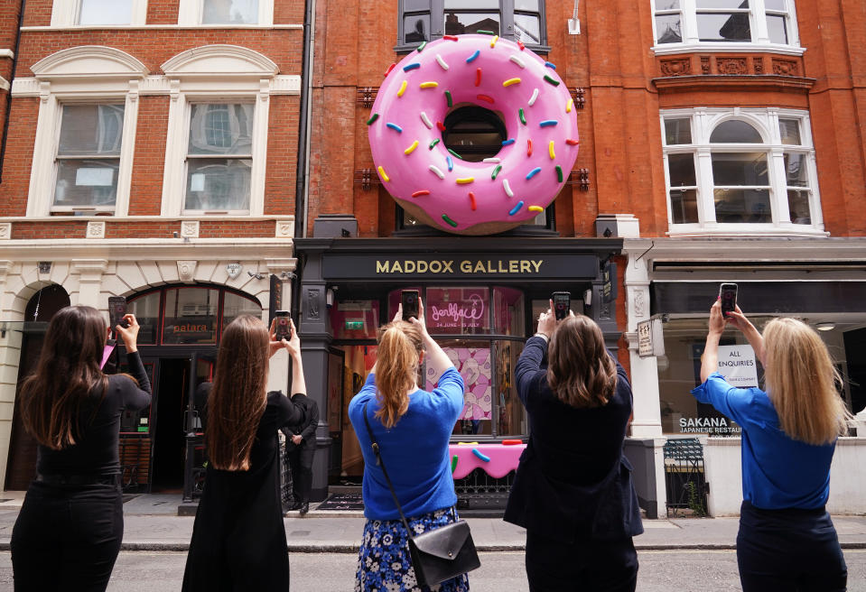 <p>A group of women take photos of a giant donut installation outside the Maddox Gallery in Mayfair, London, to celebrate a new exhibition entitled Villainy, a body of work by an anonymous street artist from New York who operates under the alias, 'Jerkface'. Picture date: Thursday June 24, 2021.</p>
