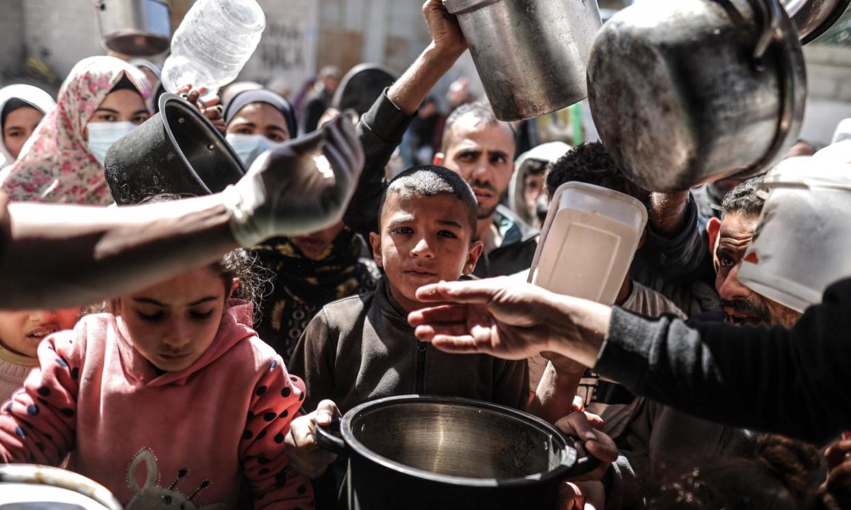 <span>Palestinian people queue for food distributed by a charity in Deir al Balah, central Gaza. Allegations against 12 employees led major donors to suspend funding to UNRWA.</span><span>Photograph: Anadolu/Getty Images</span>