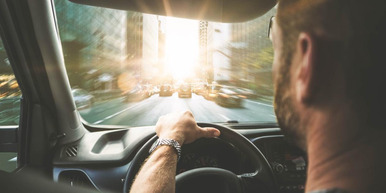 rear view of man driving car on street in city