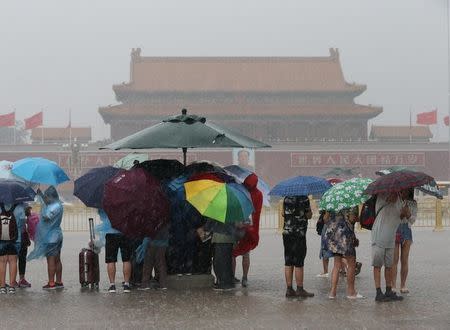 Tourists hold umbrellas as they visit Tiananmen Square during a rainstorm in Beijing, China August 12, 2017. REUTERS/Stringer