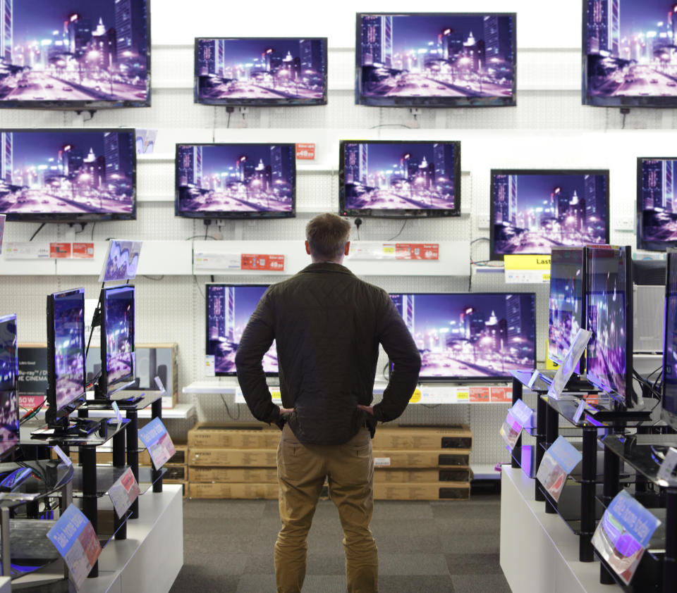 Man stood in shop surrounded by televisions