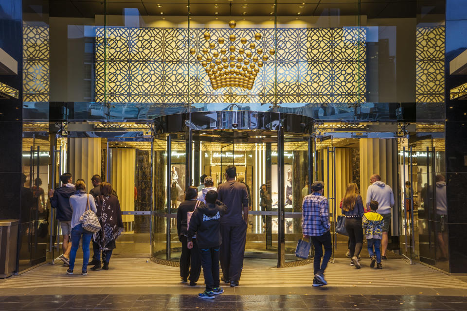 Melbourne, Australia - December 20, 2016: Groups of visitors passing through a entrance to the Crown Melbourne integrated resort in Southbank at dusk.