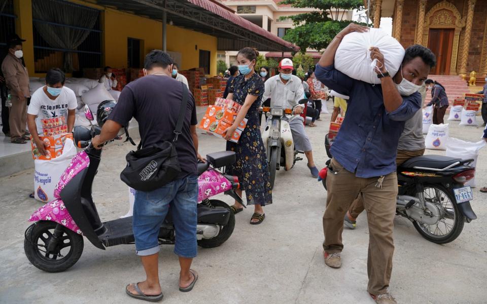 People carry sacks of rice and other food donated by the local government inside a red zone in Phnom Penh  - Cindy Liu