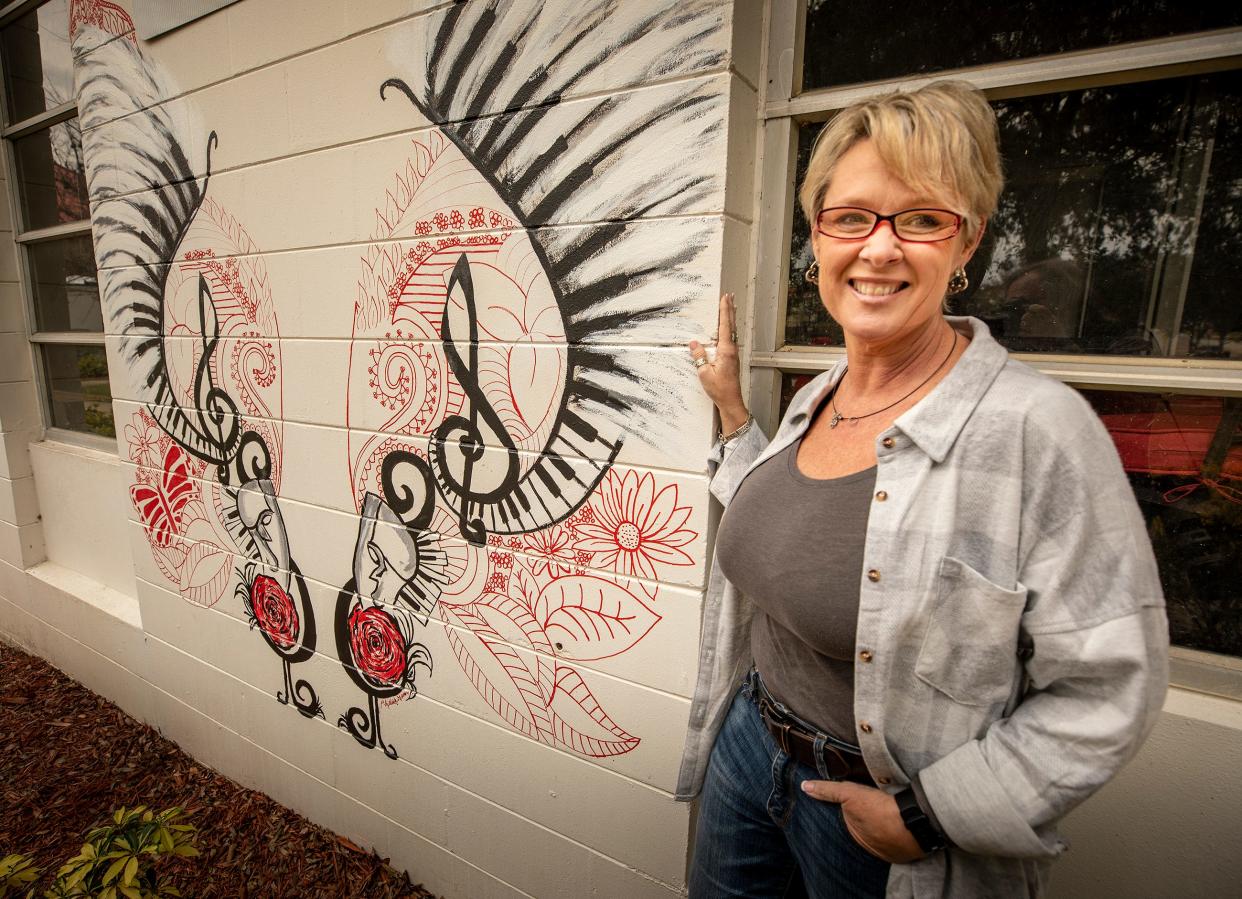 Haines City CRA Director Jane Waters Murphy stands next to the mural "Phantom of the Theater," recently paInted by Haines City native Elizabeth Gamez Bautista. The mural is the ninth in a series of wings-themed public art displays in Haines City.