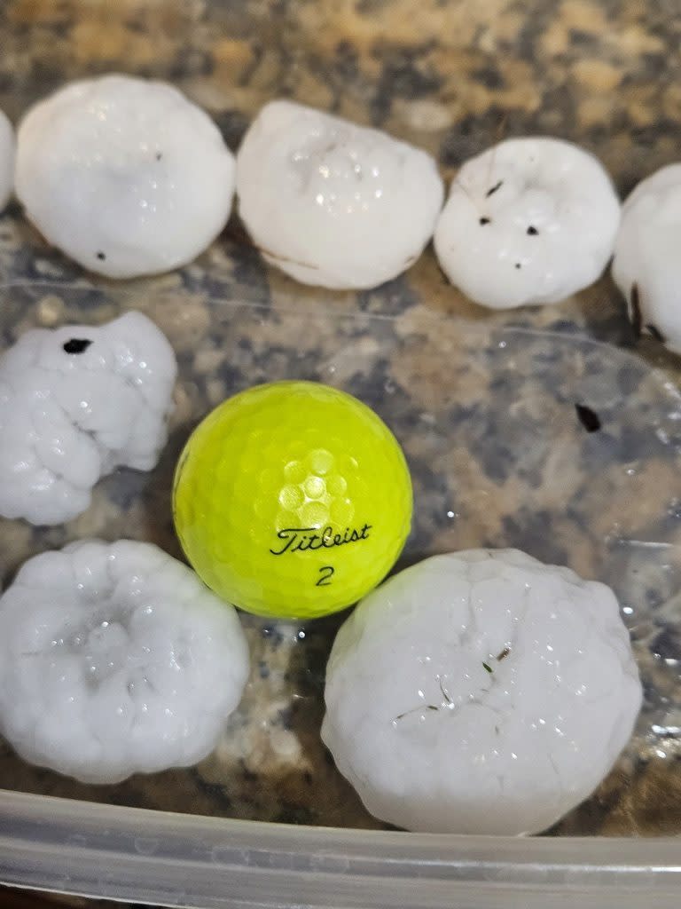 In this image provided by Randy Smith, a large chunks of hail are compared to the size of a golf ball, Wednesday night, March 13, 2024, in Shawnee, Kan. Volatile weather was honing in on parts of Kansas and Missouri Wednesday night, with some storms bringing massive chunks of hail. (Randy Smith via AP)