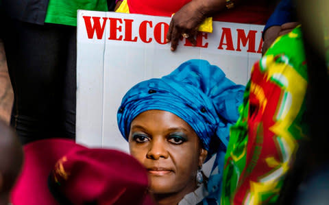 A woman holds a portrait of Grace Mugabe - Credit: AFP