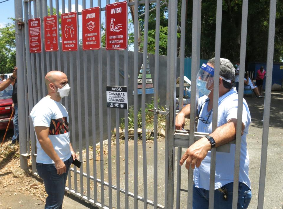 An electoral official, right, tells a voter that the ballots haven't arrived at a voting center in Carolina, Puerto Rico, Sunday, Aug. 9, 2020. Puerto Rico's primaries were marred on Sunday by a lack of ballots in a majority of centers across the U.S. territory, forcing frustrated voters who braved a spike in COVID-19 cases to turn around and go back home. (AP Photo/Danica Coto)