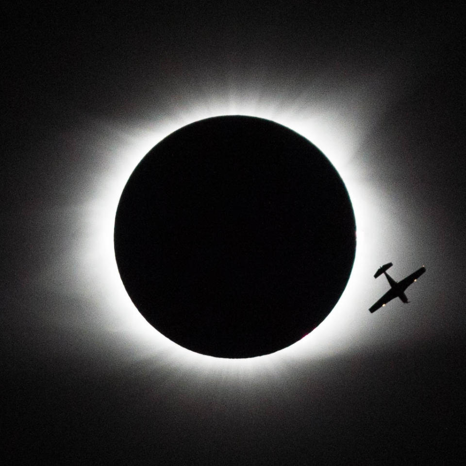 A small plane is silhouetted by a total eclipse.