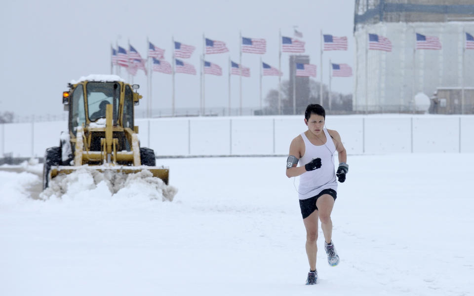 Snow is plowed behind a jogger running on the Washington Monument grounds in Washington, Monday, March 17, 2014. (AP Photo/Susan Walsh)