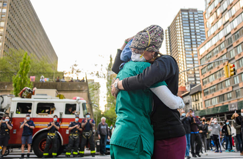 Medical workers hug outside NYU Langone Health hospital as people applaud to show their gratitude for them during the coronavirus pandemic, May 7, 2020. (Photo by Noam Galai/Getty Images)