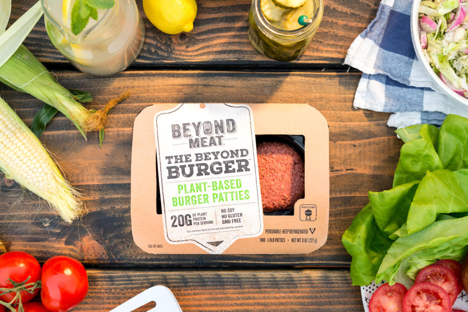 A package of Beyond Meat burgers surrounded by a variety of toppings and condiments.