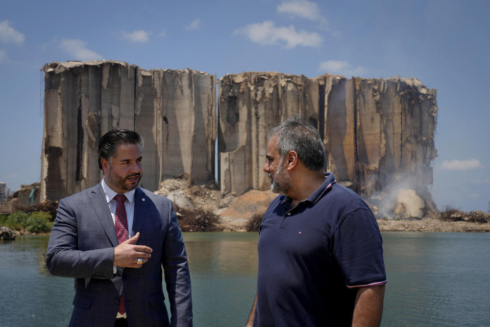 Lebanese caretaker Economy Minister Amin Salam, left, speaks with Beirut Port Silos General Manager Assad Haddad near Beirut Port silos, that were destroyed by a massive explosion in 2020, in Beirut, Lebanon, Thursday, July 14, 2022. Salam said Thursday that the capital's port silos, shredded in a massive blast two years ago may collapse, as authorities struggle to contain a fire. (AP Photo/Bilal Hussein)