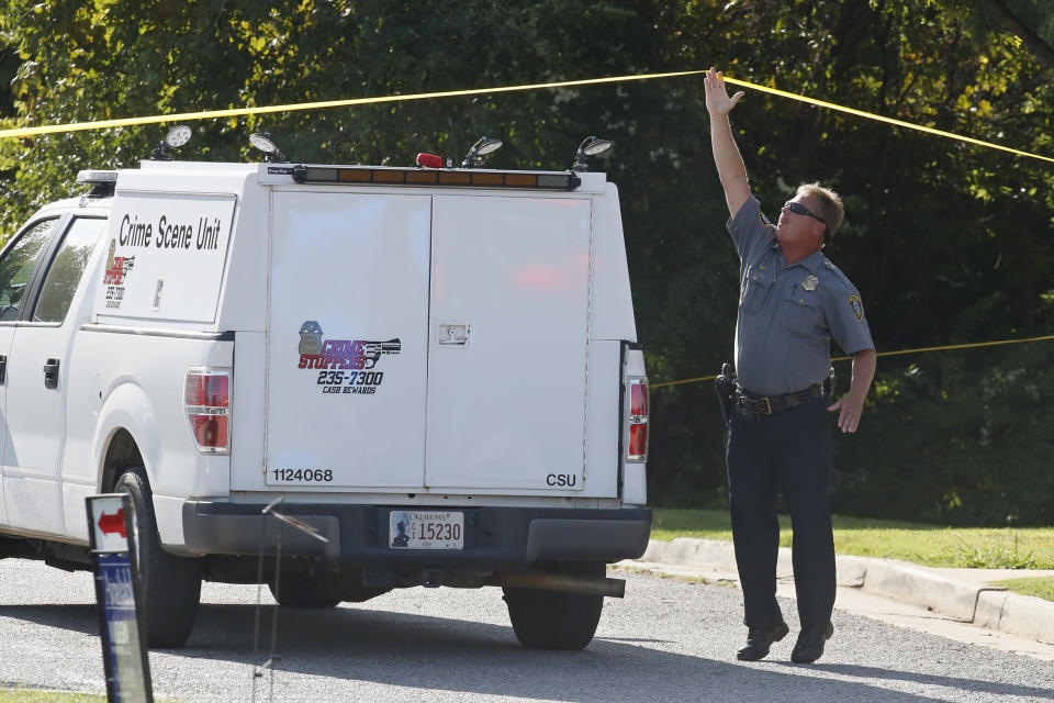 A police officer stretches to raise crime scene tape for a crime scene unit to pass under at the scene where a shooting suspect was fatally shot during a police chase in Monday, Sept. 9, 2019, in northwest Oklahoma City. (AP Photo/Sue Ogrocki)