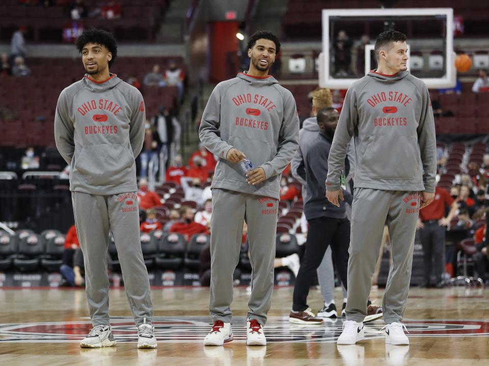 Injured Ohio State Buckeyes, from left, Justice Sueing, Seth Towns and forward Kyle Young (25) watch teammates warm up prior to the NCAA exhibition basketball game against the Indianapolis Greyhounds at Value City Arena in Columbus on Monday, Nov. 1, 2021. 