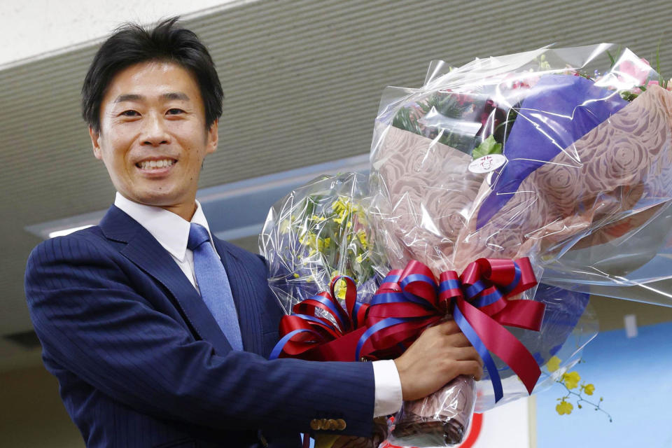 Former prefectural assembly member Shinnosuke Yamazaki poses with bouquets of flowers after winning a seat in by-elections, supported by opposition groups, in Shizuoka, central Japan, Sunday, Oct. 24, 2021. Japanese Prime Minister Fumio Kishida lost one of two parliamentary seats contested in the weekend by-elections seen as a major test ahead of a crucial national vote that could determine how long his government may last. (Kyodo News via AP)