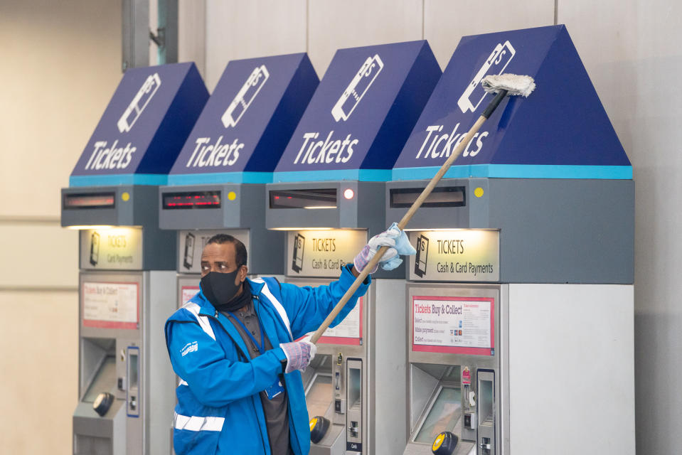 A member of staff wearing a protective face mask cleans ticket machines at London Bridge station in London, as train services increase as part of the easing of coronavirus lockdown restrictions. (Photo by Dominic Lipinski/PA Images via Getty Images)