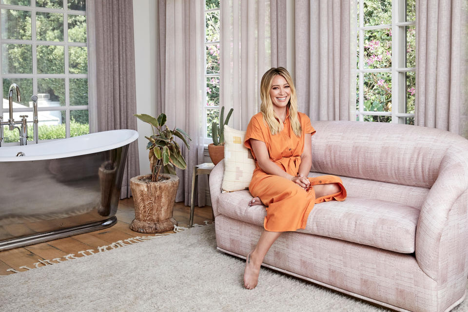 Hilary Duff sits in her bathroom, which is like her own private sanctuary (she even takes guitar lessons in there!) (Jenna Peffley / Architectural Digest)