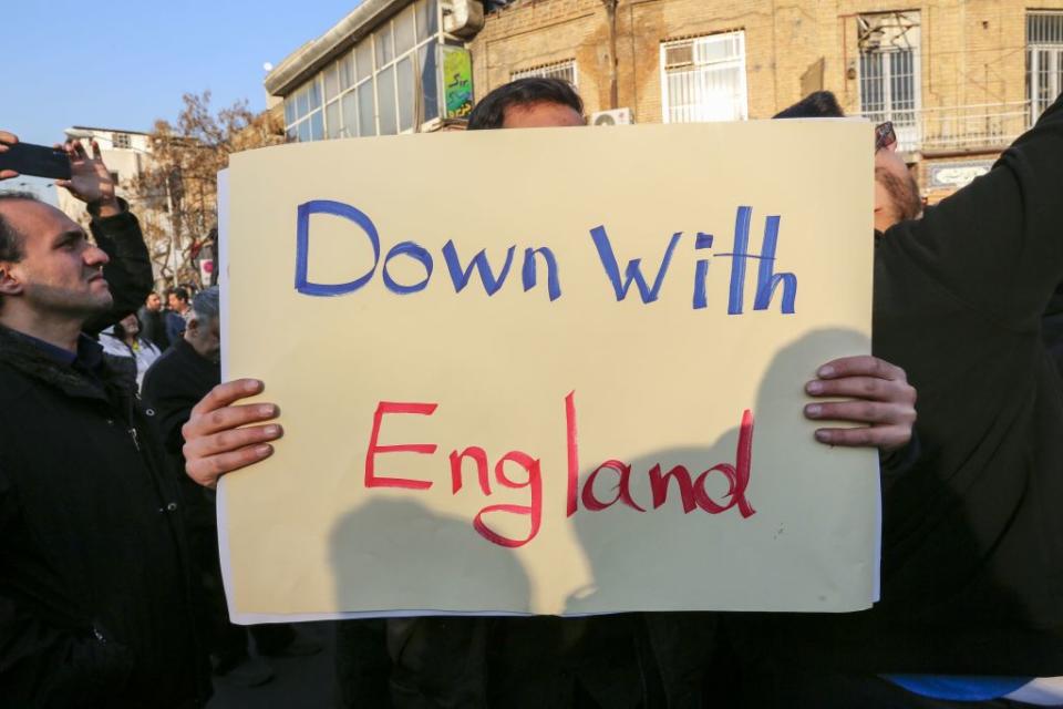 An Iranian protester holds a "Down with England" placard outside the British embassy in Tehran on Sunday (Picture: AFP/Getty)