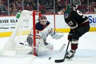 Edmonton Oilers goaltender Mikko Koskinen, left, makes a save on a shot as Arizona Coyotes right wing Dmitrij Jaskin (93) tries to control the puck during the first period of an NHL hockey game Thursday, Oct. 21, 2021, in Glendale, Ariz. (AP Photo/Ross D. Franklin)