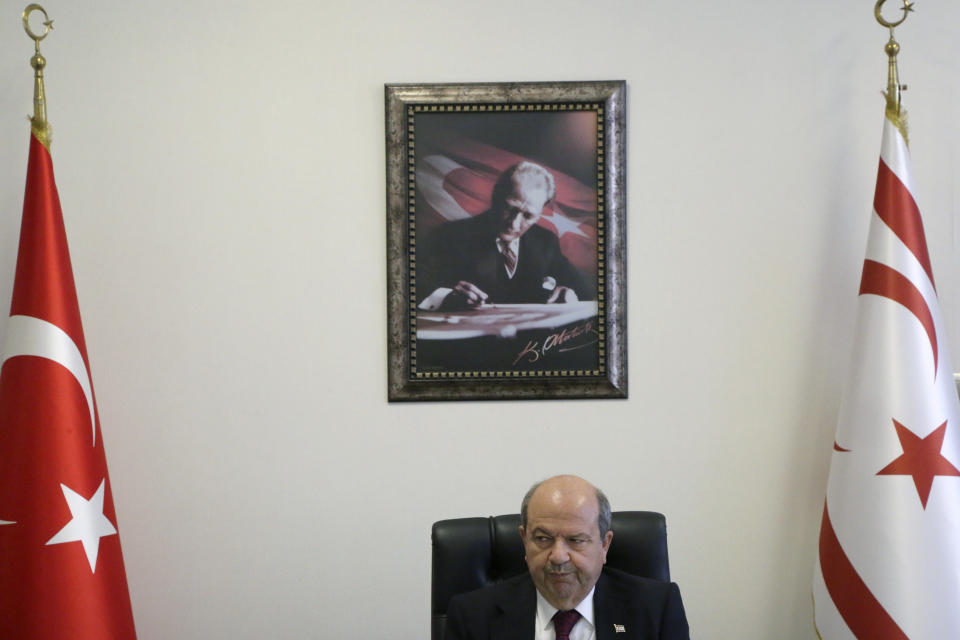 Ersin Tatar, prime minister of a self-declared Turkish Cypriot state recognized only by Turkey sits at his office as a wall decorated with a picture of modern Turkey's founder Mustafa Kemal Ataturk, in the Turkish occupied area in north part of divided capital Nicosia, Cyprus, Tuesday, March 3, 2020. Tatar says ongoing tensions over a hydrocarbons search off ethnically divided Cyprus would fade if Greek Cypriots drop their objections and agree to divvy up the country's territorial waters and drilling rights with breakaway Turkish Cypriots. (AP Photo/Petros Karadjias)