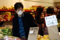 A man wears a face mask shopping at a market in the Chinatown section of San Francisco, California