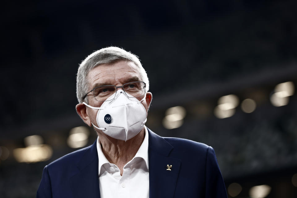 International Olympic Committee President Thomas Bach, wearing a face mask, speaks to the media.