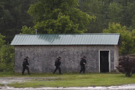 Law enforcement officers search a building on a farm near Willsboro, New York June 9, 2015. REUTERS/Chris Wattie