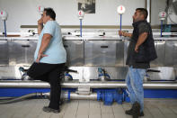 Neilos Papachristou, left, who runs the olive mill and nearby grove in a fourth-generation family business, stands with a worker at a machine in Spata suburb, east of Athens, Greece, Monday, Oct. 23, 2023. Across the Mediterranean, warm winters, massive floods, and forest fires are hurting a tradition that has thrived for centuries. Olive oil production has been hammered by the effects of climate change, causing a surge in prices for southern Europe's healthy staple. (AP Photo/Thanassis Stavrakis)