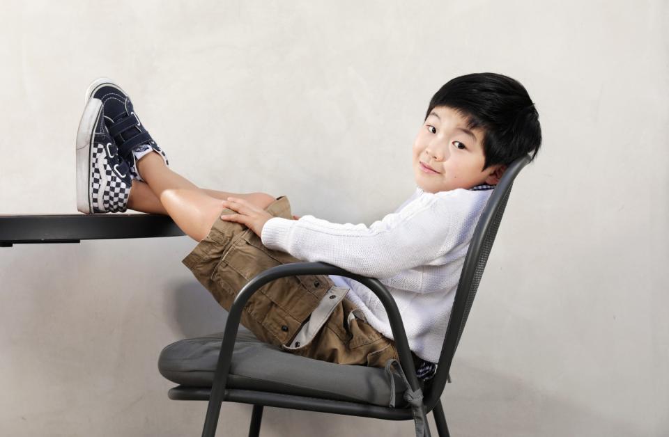 Eight-year-old Alan Kim sits with his feet up on a desk.