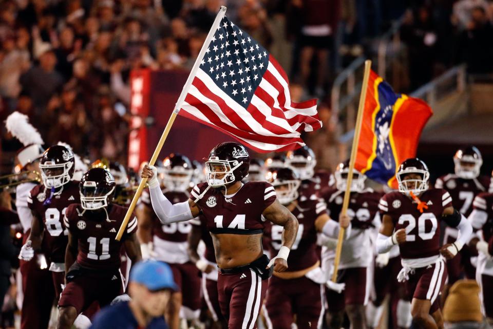 Nov 23, 2023; Starkville, Mississippi, USA; Mississippi State Bulldogs linebacker Nathaniel Watson (14) carries an American Flag onto the field prior to the game against the Mississippi Rebels at Davis Wade Stadium at Scott Field. Mandatory Credit: Petre Thomas-USA TODAY Sports